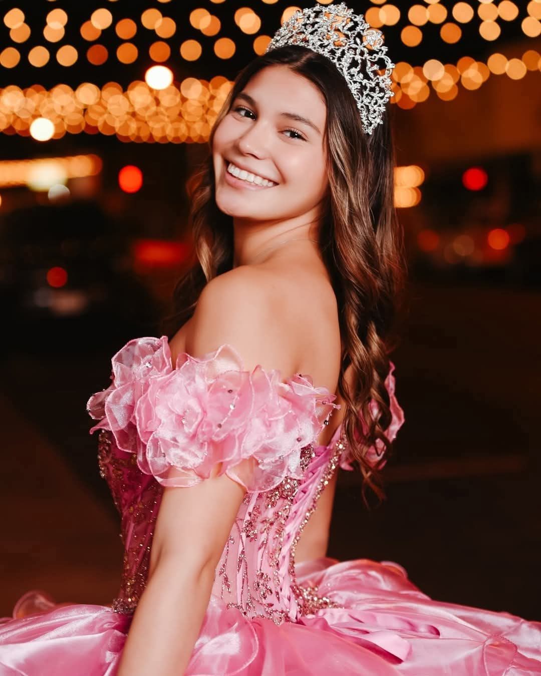 Pink off-shoulder quinceañera ballgown with floral straps and tiara